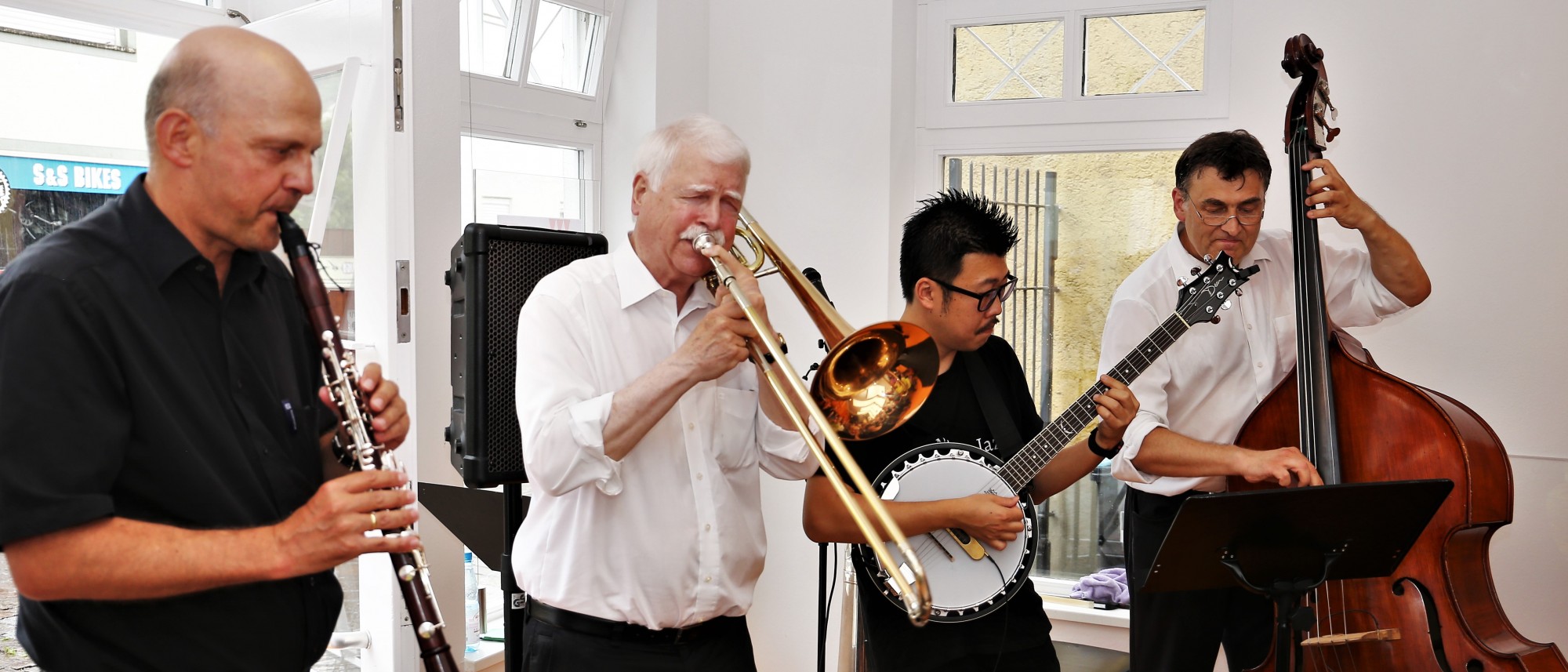 Vier Musiker mit Klarinette, Posaune, Banjo und Kontrabass beim Konzert im Museumsfoyer.